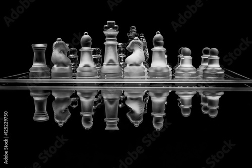 Black and white glass chess set with reflection photo