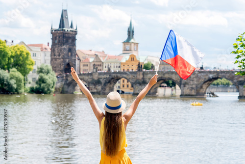 Young female tourist with raised hands holding czech flag on the old town background in Prague. photo