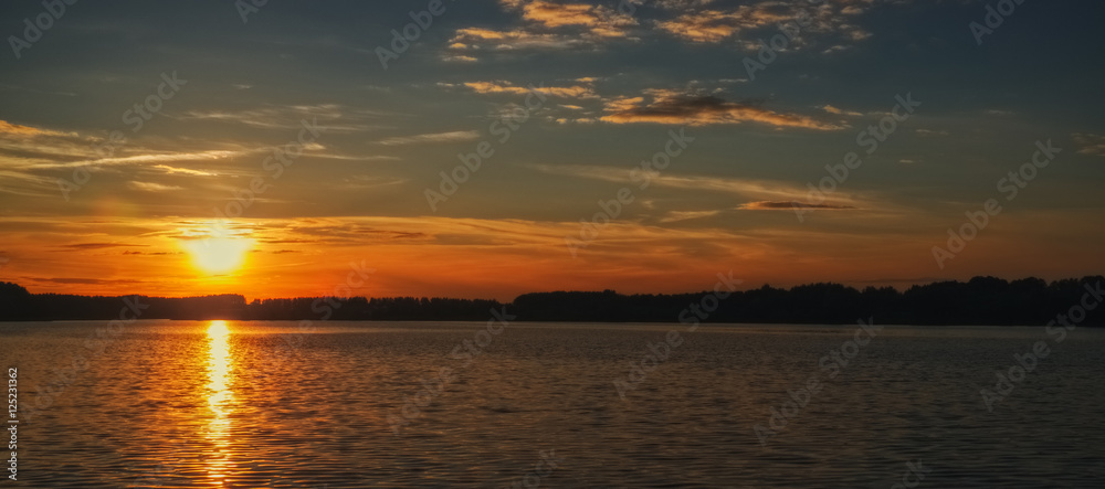 Toned photo of sunset over the lake with forest on the opposite