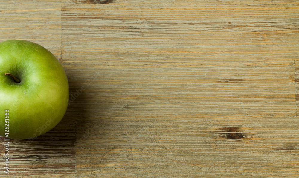 Green apple on a wooden table half visible Green apple on a wooden table half visible
