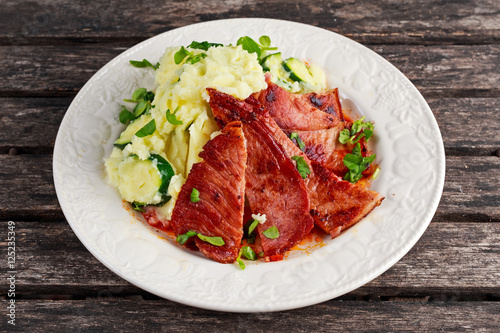 Sliced Gammon Steak with mashed potato on wooden background.
