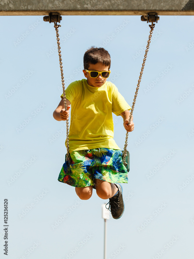 Boy playing swinging by swing-set.