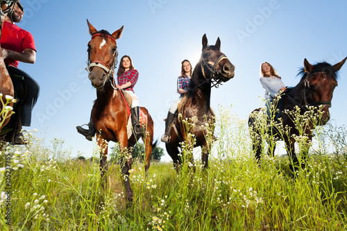 Group of happy horse riders in flowery meadow