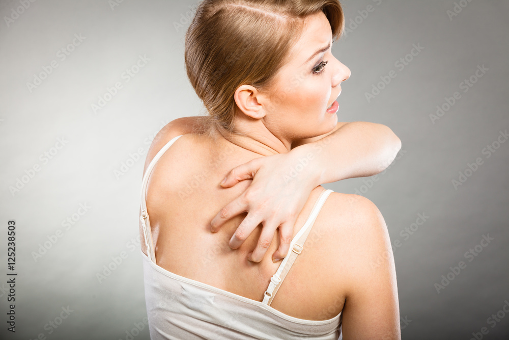 woman scratching her itchy back with allergy rash woman scratching her itchy back with allergy rash