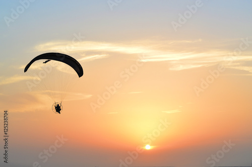 the silhouette of a flying paraglider