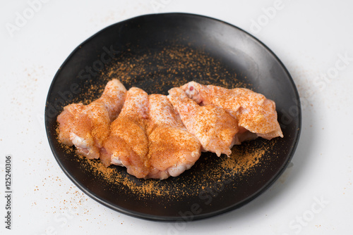 Fresh raw chicken meat seasoned with spices and chili on black d