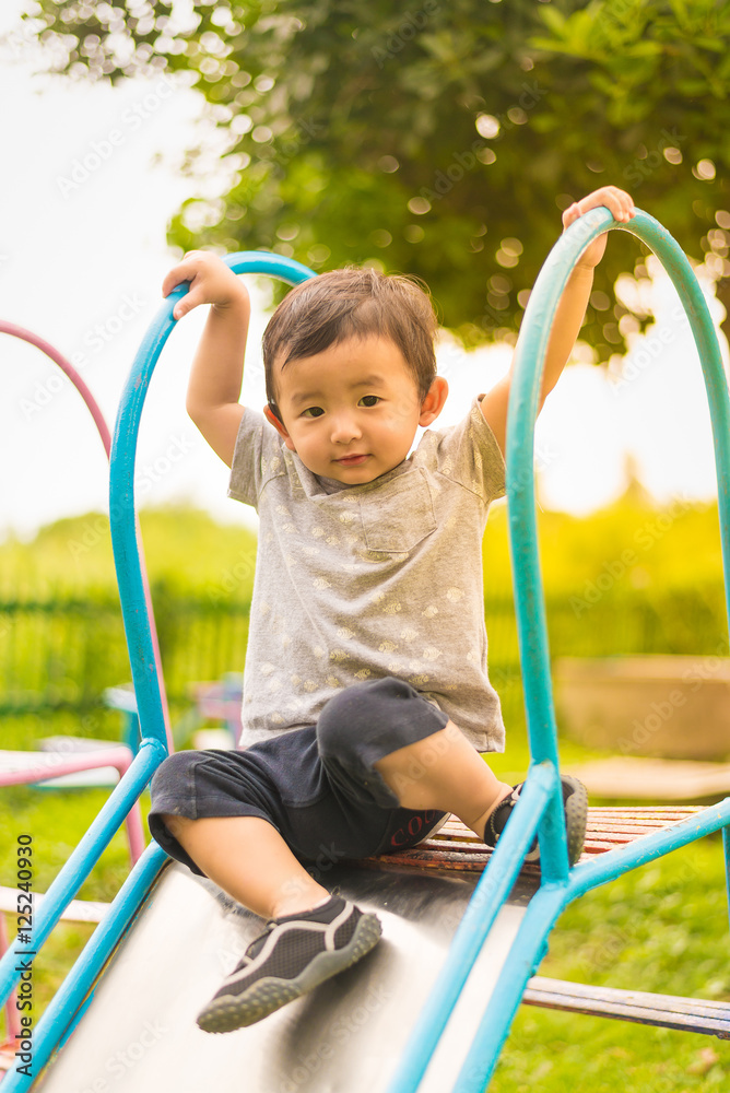Little Asian kid playing slide at the playground Little Asian kid playing slide at the playground