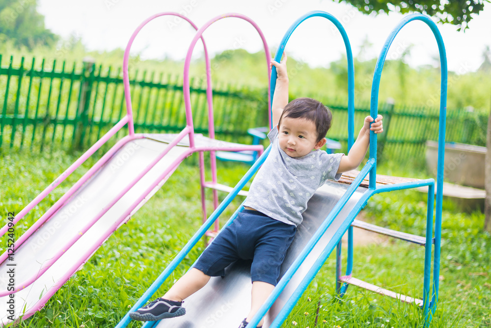 Little Asian kid playing slide at the playground Little Asian kid playing slide at the playground