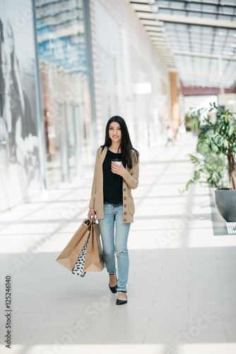 Attractive cute girl in with the shopping bags and warm drink in her hand