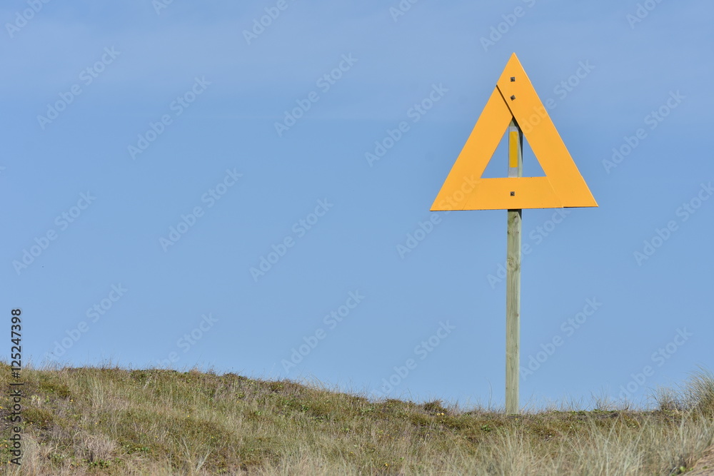 Large yellow triangle sign on pole on top of sand dune showing marine reserve protected area border. Large yellow triangle sign on pole on top of sand dune showing marine reserve protected area border.