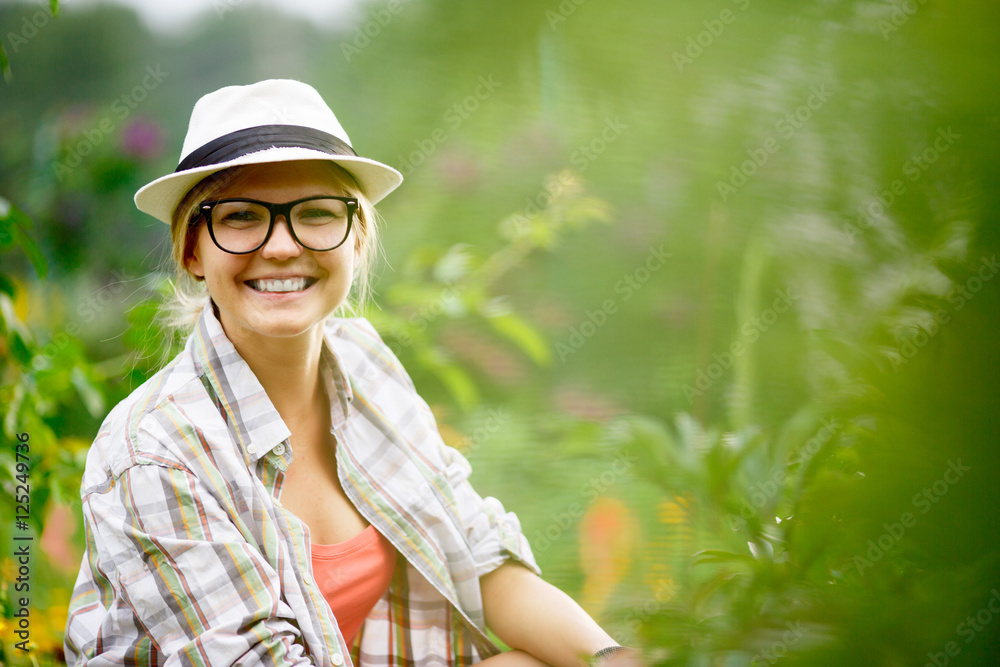 Young caucasian smiling woman caring for plants in her garden
