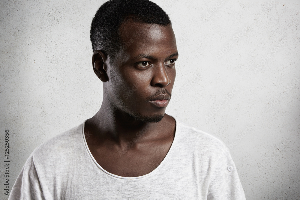 Φωτογραφία Side view portrait of pensive African man wearing white T-shirt with low necklin