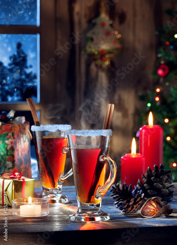 close up view of glasses with mulled wine with gift boxes on color back