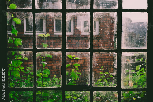 Altes Sprossenfenster in einer historischen Werkshalle mit Ausblick auf ein historisches Fabrikgebäude aus Backstein. photo