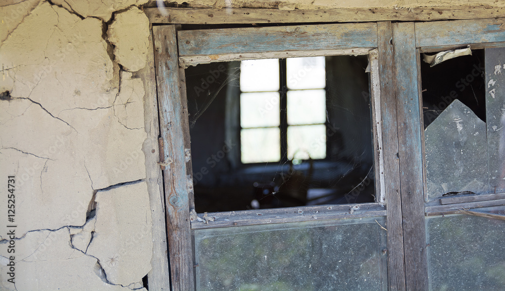 Rickety old wooden window frame with broken window pane. Part of old mud hut facade covered with a cracks. Rickety old wooden window frame with broken window pane. Part of old mud hut facade covered with a cracks.