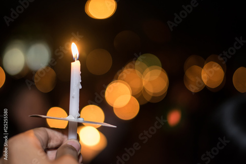 Blurred image for background of hand with candle memorable for King Bhumibol Adulyadej of thailand
