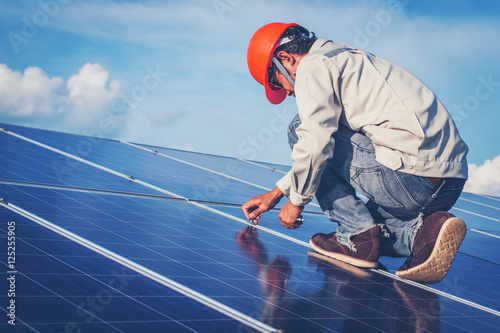 employee working on Wrench tightening solar mounting structure of photovoltaic panel at industry solar power 