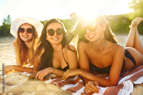 summer holidays and vacation - girls sunbathing on the beach. young and beautiful girls enjoying the summer time. beautiful figure