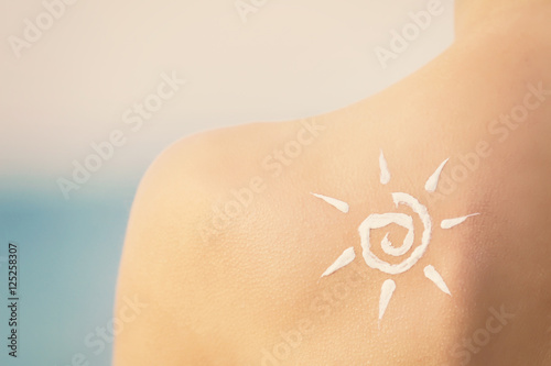 Woman with sunscreen in sun shape on shoulder. Skin care concept.