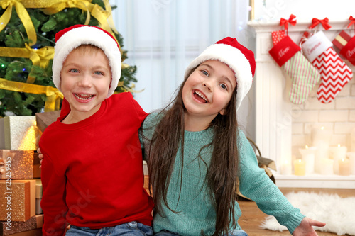 Cute little kids in Santa hats at home