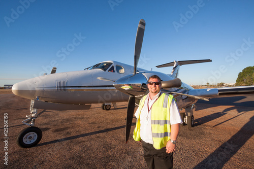 Young corporate pilot in high visability vest standing by left e photo