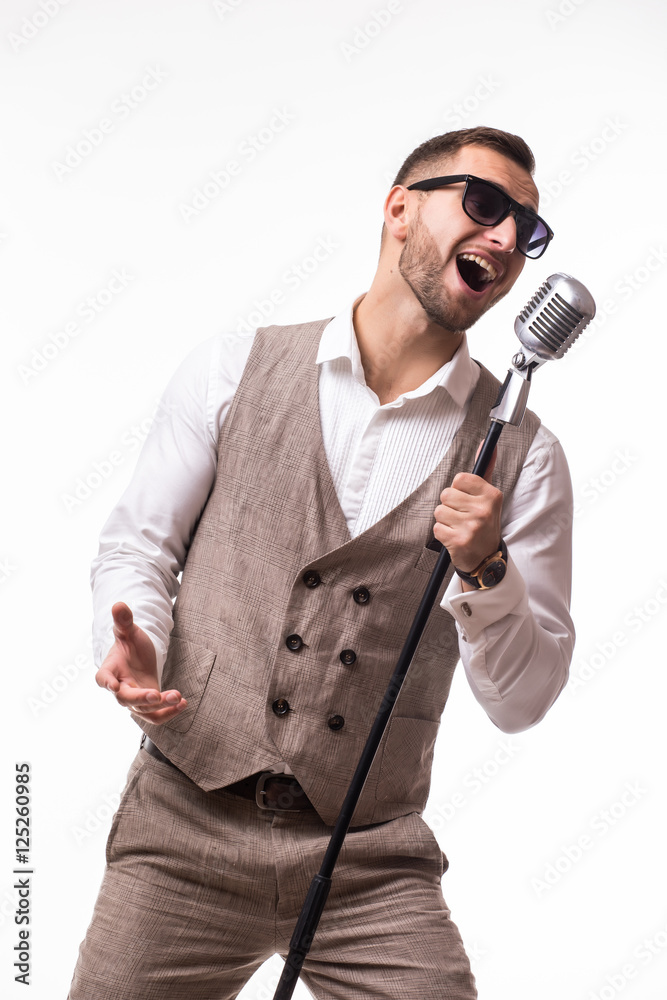 portrait of young man in suit singing with the microphone. Isolated on grey background. Singer concept. portrait of young man in suit singing with the microphone. Isolated on grey background. Singer concept.