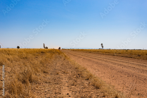 Outback road on a vast plain with approaching vehicle in the Kimberley photo