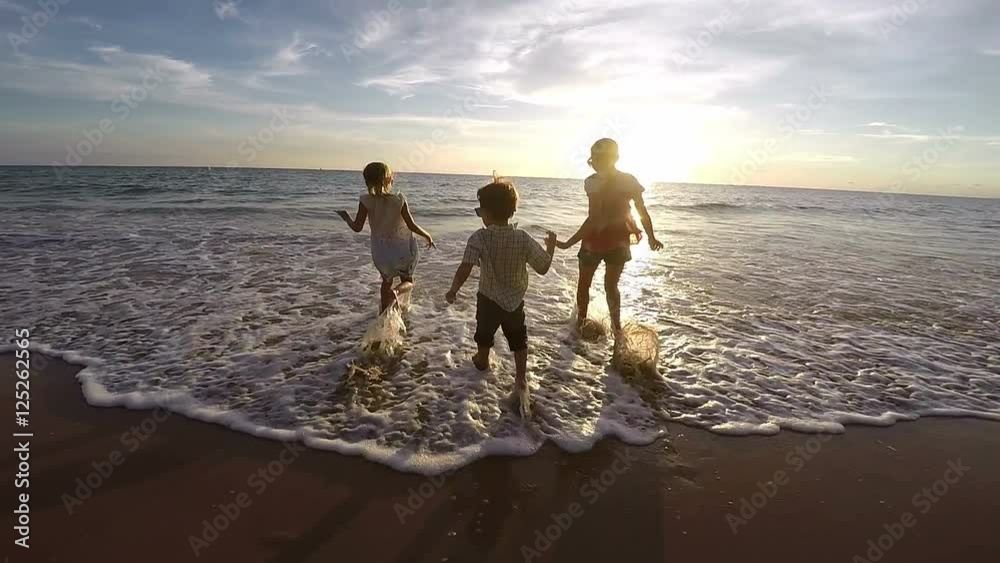 Happy children playing on the beach at the sunset time. Concept of happy friendly family. Video filmed on camera Gopro. 