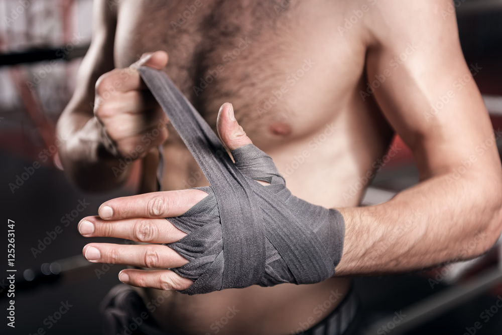Close up of man wrapping hand in boxing tape
