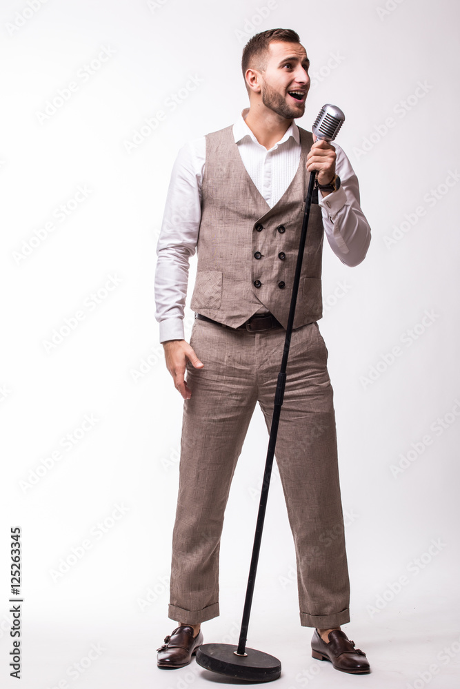 Naklejka premium Young showman in suit singing with emotions gesture over the microphone with energy. Isolated on white background. Singer concept.