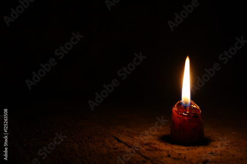 Маленькая свеча в очень темной комнате на старых досках 