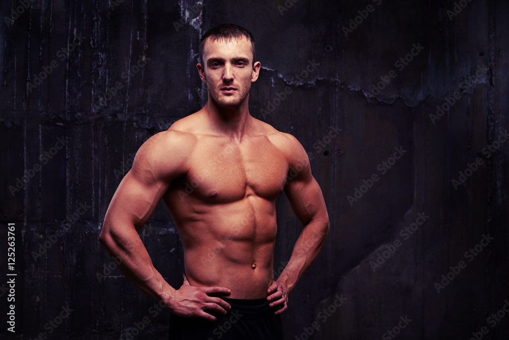 Bare-chested handsome man with reliefed muscles standing half-tu