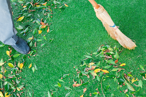 Working with broom sweeps lawn from fallen leaves