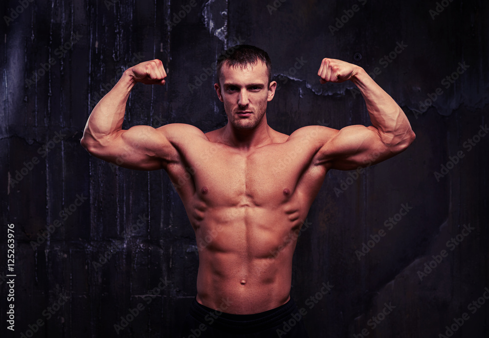Obraz premium Man with perfect abs, shoulders, biceps, triceps and chest is po