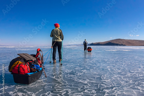 a woman and a man with a sledge and trekking pole is ice of Baik photo