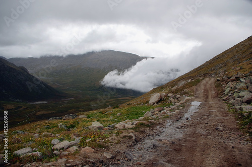Extreme rocky stone road way in a mountain valley to the pass in cloudy weather with rain and fog Plateau Ukok Altai Siberia Russia