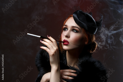 Tableau sur toile Beautiful girl with smoky eyes and red lips holding cigarette