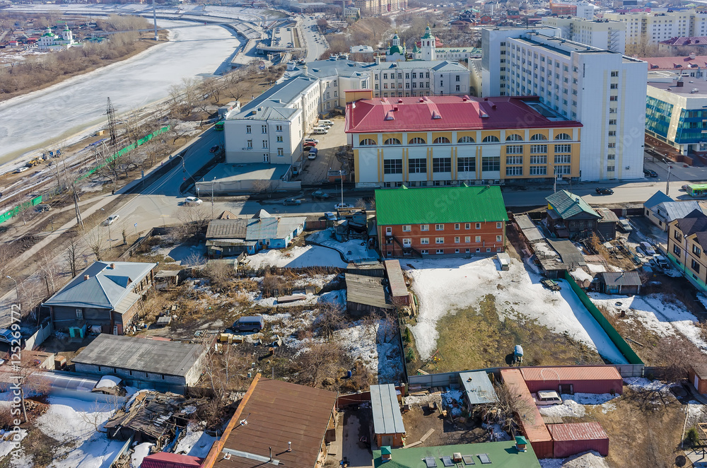 Tyumen, Russia - April 3, 2015: Tura river. Tyumen industrial university and private houses on Yamskaya street