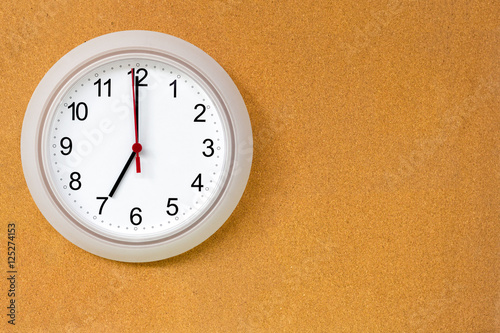 Round clock at 7 o'clock hanging on brown board
