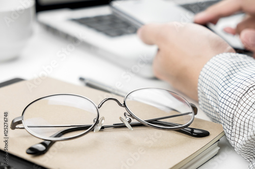 Close-up of eye glasses with a business man using his smartphone in the background behind.