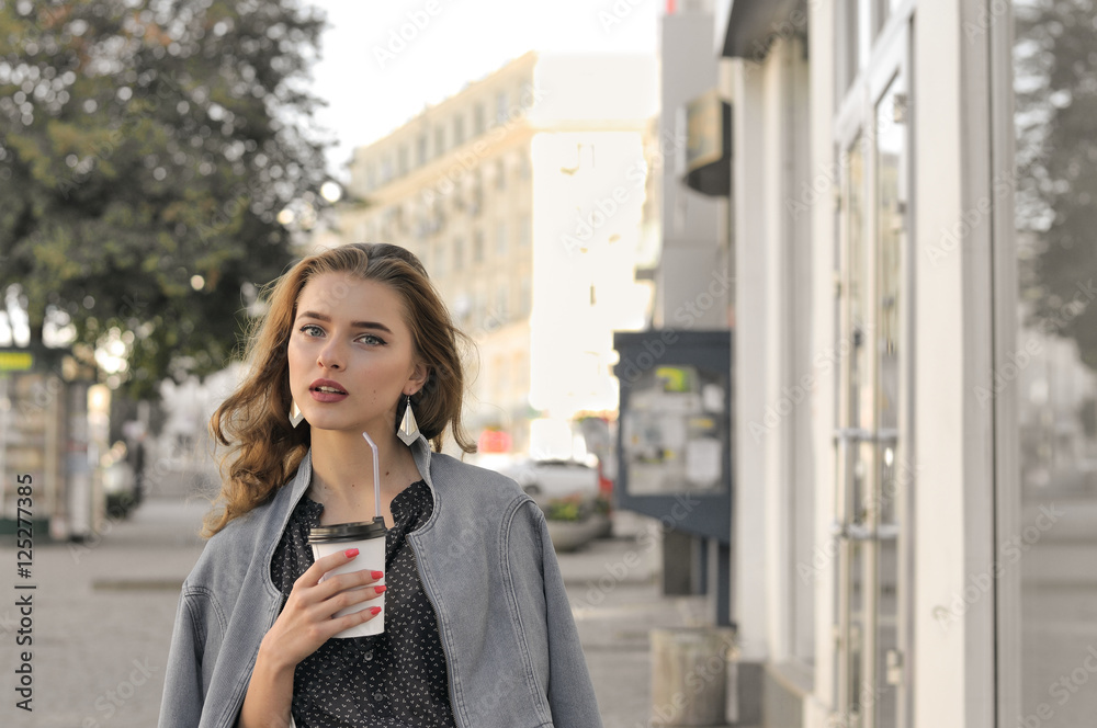 Girl goes on the sidewalk and drinking coffee Girl goes on the sidewalk and drinking coffee