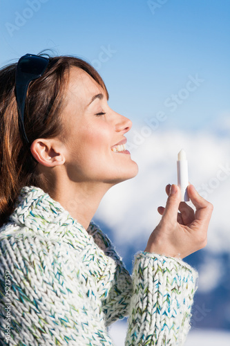 portrait d'une belle femme souriant qui applique du stick de protection solaire sur sa bouche