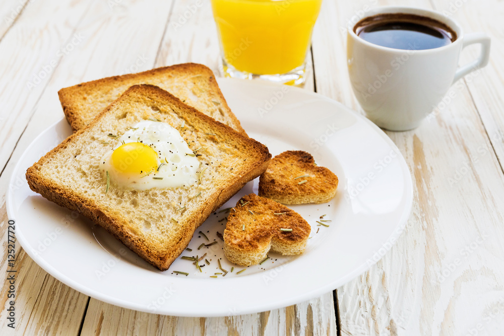 Egg fried in a heart-shaped toast cutout sprinkled Egg fried in a heart-shaped toast cutout sprinkled