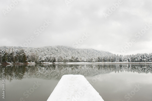 pier covered with snow against backdrop of lake and snow-covered trees photo