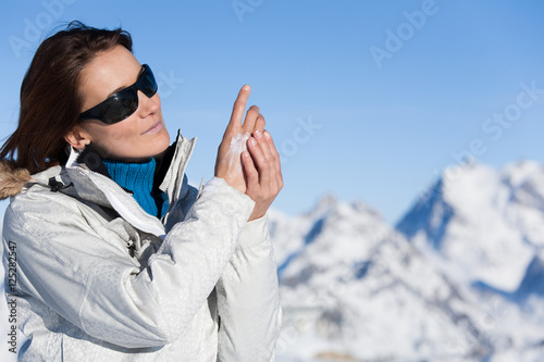 portrait d'une femme se mettant de la crème sur les mains en hiver à la neige