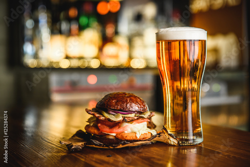 Fotografia Hamburger and light beer on a pub background.