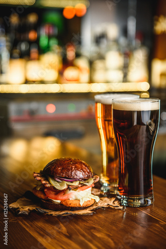 Hamburger and dark light beer on a pub background.