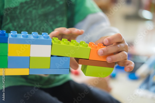 Closeup of asian kid's hand playing plastic blocks, puzzle