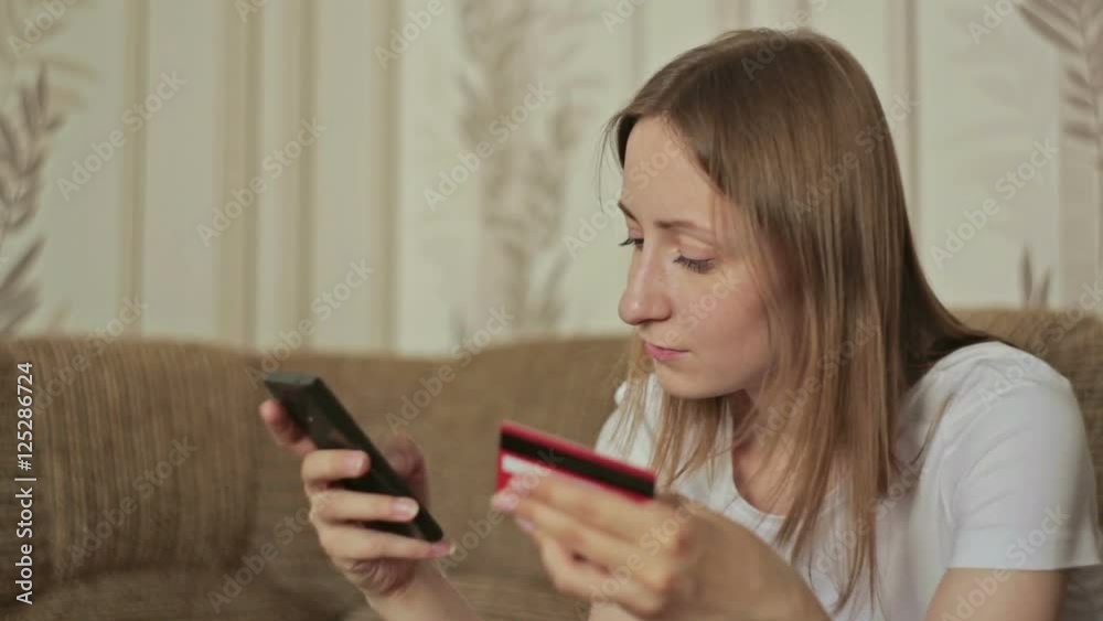Female buying goods from the internet on her smartphone with her credit card. Young woman caucasian hands entering number security code from credit card on mobile phone Female buying goods from the internet on her smartphone with her credit card. Young woman caucasian hands entering number security code from credit card on mobile phone