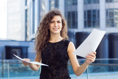 Fotografía Curly girl holds documents in hand, confusion